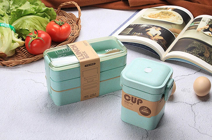 A stylish microwave-safe lunch box with a removable soup mug in various colours, including pink, green, and apricot