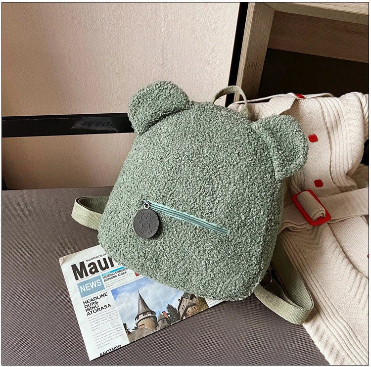 Adorable bear-shaped backpack made of soft fleece material in various colors, featuring a spacious main compartment and adjustable shoulder straps for comfortable wear.