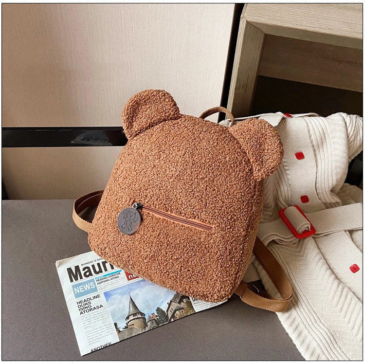 Adorable bear-shaped backpack made of soft fleece material in various colors, featuring a spacious main compartment and adjustable shoulder straps for comfortable wear.