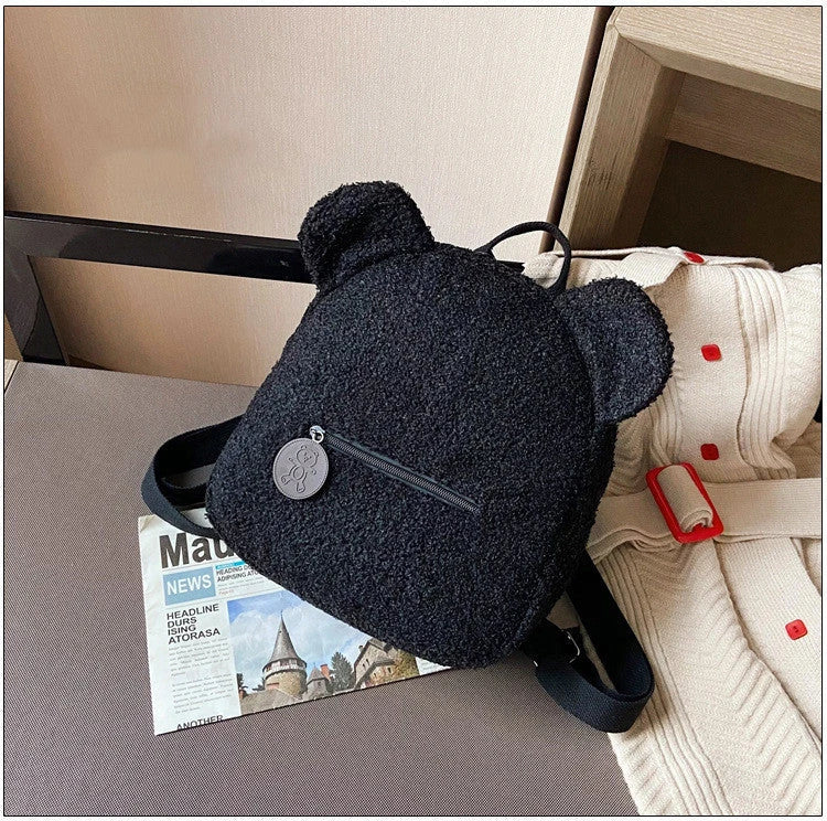 Adorable bear-shaped backpack made of soft fleece material in various colors, featuring a spacious main compartment and adjustable shoulder straps for comfortable wear.