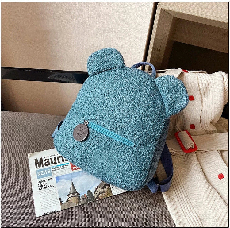 Adorable bear-shaped backpack made of soft fleece material in various colors, featuring a spacious main compartment and adjustable shoulder straps for comfortable wear.