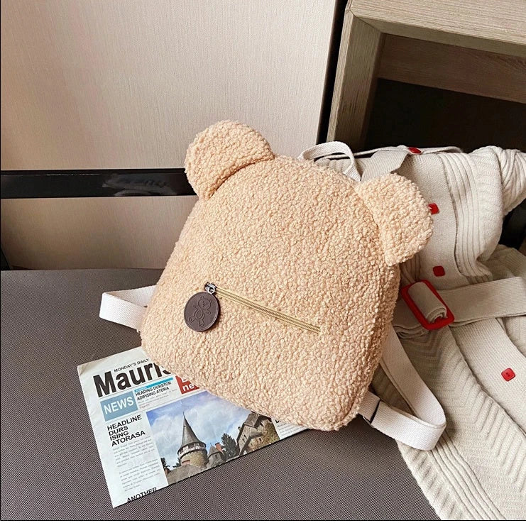 Adorable bear-shaped backpack made of soft fleece material in various colors, featuring a spacious main compartment and adjustable shoulder straps for comfortable wear.
