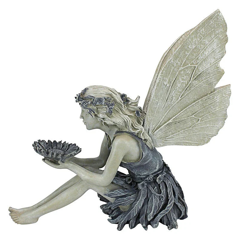 A beautiful resin fairy garden statue with a flower crown and petal skirt, holding a sunflower bowl to attract birds