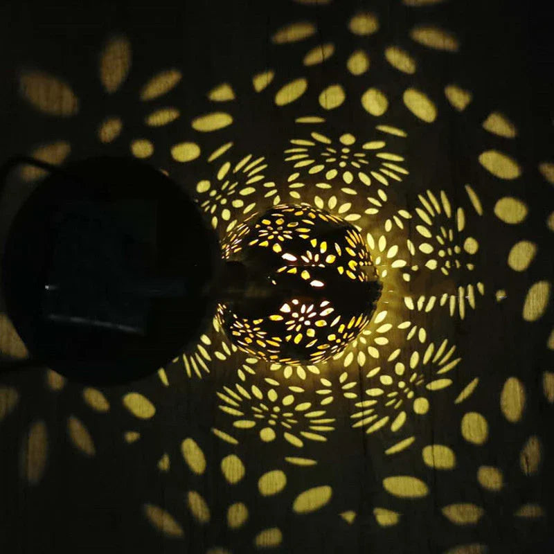 Solar-powered outdoor hanging lantern with flower-patterned shade, made of durable metal for long-lasting use in gardens, patios, and pathways.