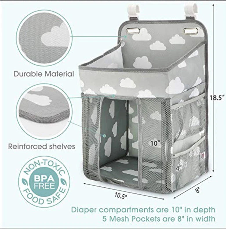 A gray crib-side organizer hanging on a white crib, storing various baby items like diapers, bottles, and toys.