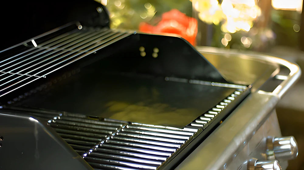 Two black nonstick BBQ grill mats on a grill, perfect for retaining juices and flavours while preventing food loss.