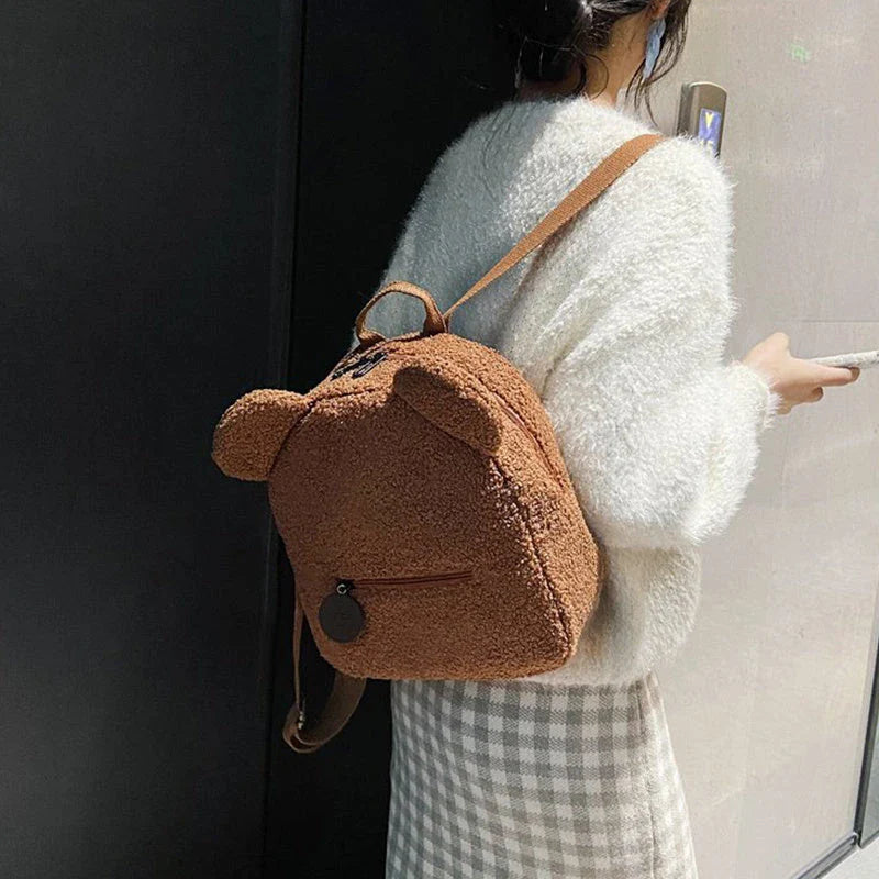 Adorable bear-shaped backpack made of soft fleece material in various colors, featuring a spacious main compartment and adjustable shoulder straps for comfortable wear.