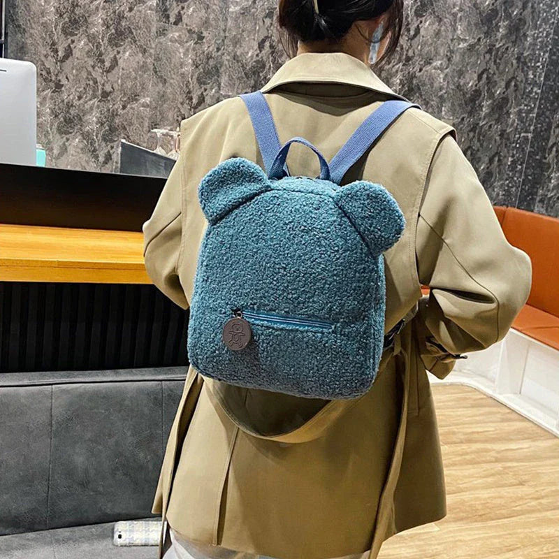 Adorable bear-shaped backpack made of soft fleece material in various colors, featuring a spacious main compartment and adjustable shoulder straps for comfortable wear.