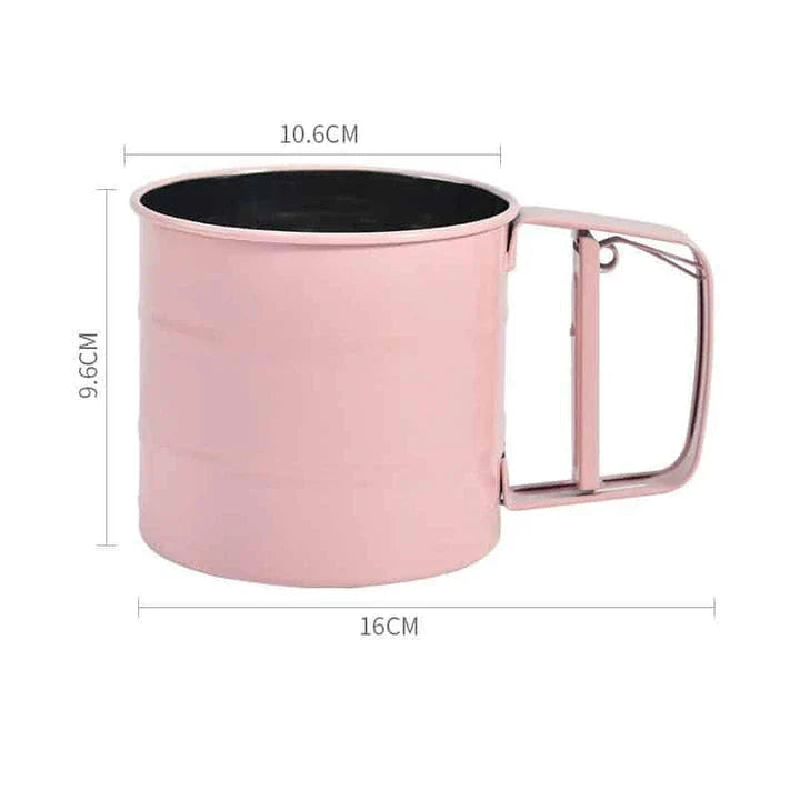 Stainless steel handheld baking flour sifter in a soft pink colour, designed for efficient sifting and aeration of dry ingredients for light and fluffy baked goods.