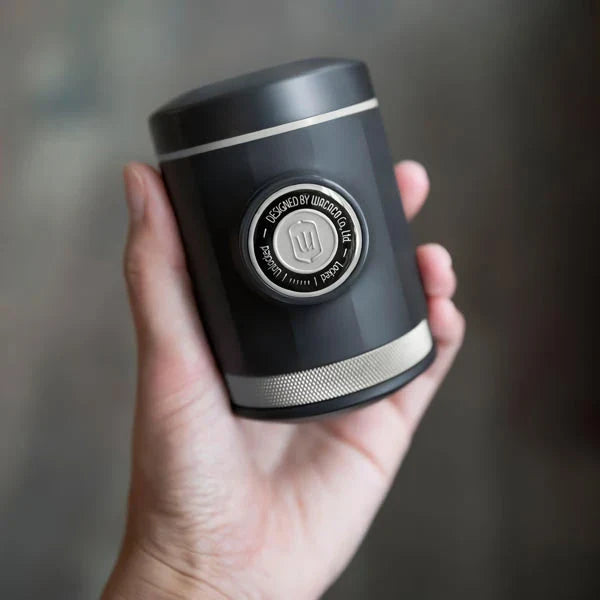 Portable espresso maker with a sleek black design, featuring a naked portafilter and manual operation for crafting premium coffee on the go.