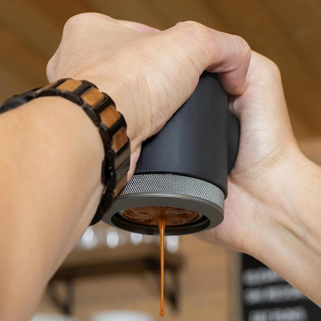 Portable espresso maker with a sleek black design, featuring a naked portafilter and manual operation for crafting premium coffee on the go.