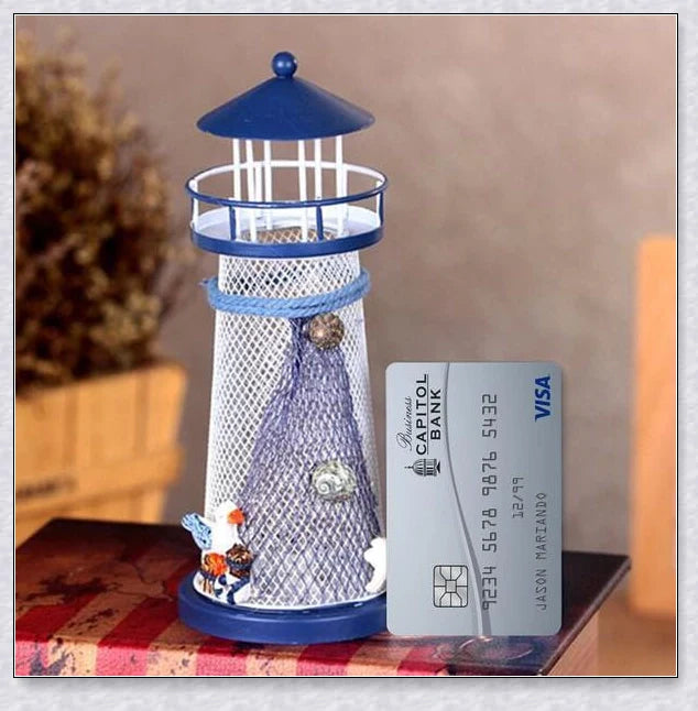 Oceanica LED Lighthouse Lantern Nightlight with nautical details like a small boat, life buoy, and seashells, providing a soft warm glow.