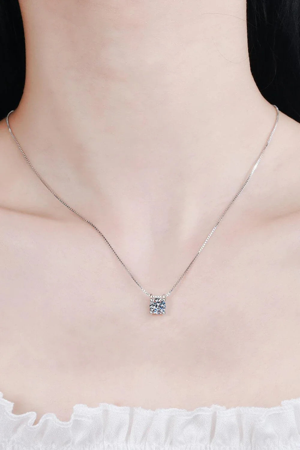 Closeup view of a sparkling 1 carat moissanite gemstone set in a rhodium-plated 925 sterling silver chain necklace