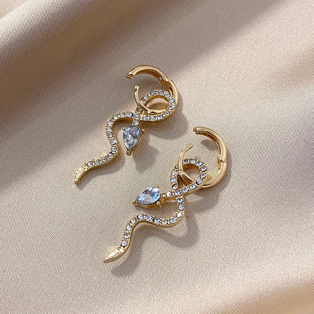 Elegant gold-toned snake charm earrings with a dangle design, perfect for adding a touch of sophistication to any outfit.