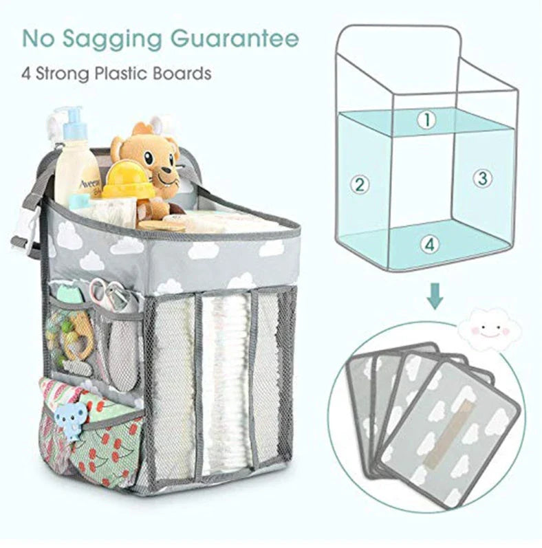 A gray crib-side organizer hanging on a white crib, storing various baby items like diapers, bottles, and toys.