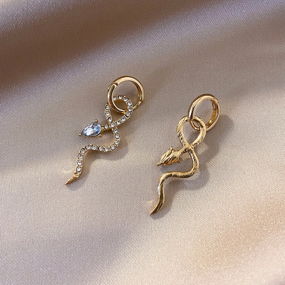 Elegant gold-toned snake charm earrings with a dangle design, perfect for adding a touch of sophistication to any outfit.