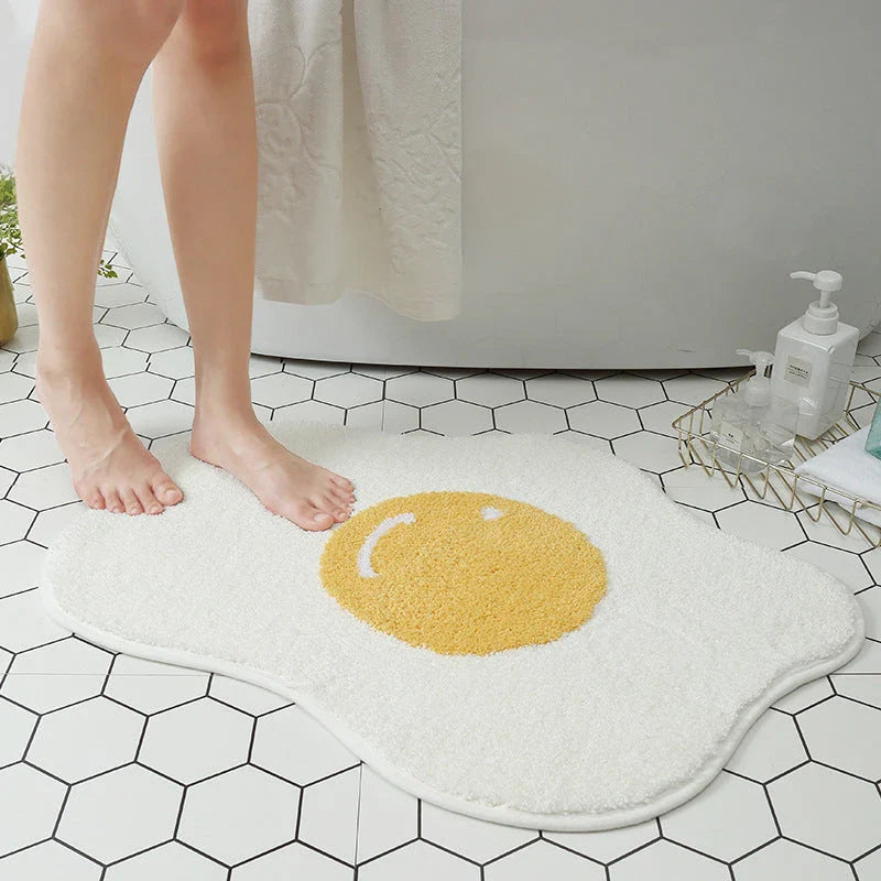 Quirky egg-shaped entrance mat made of absorbent polyester fabric with non-slip rubber backing, available in various sizes and colours