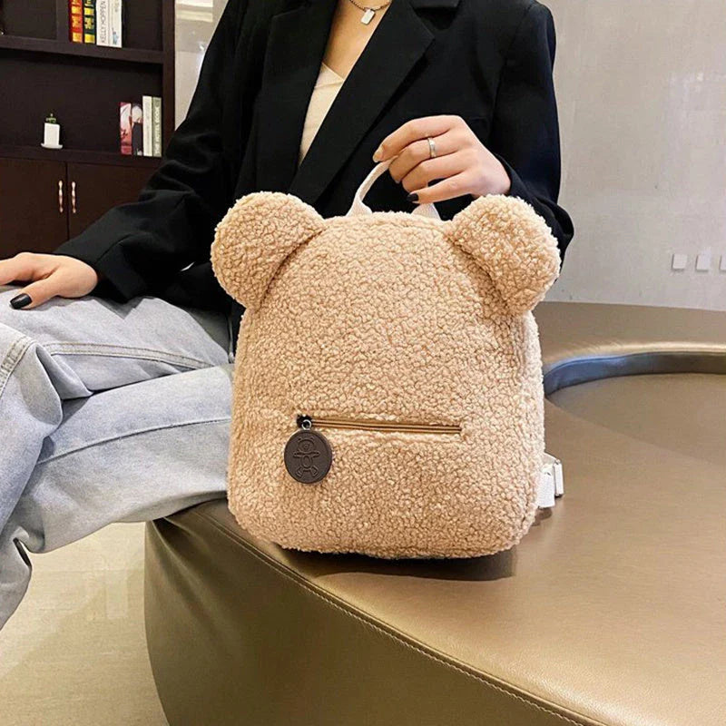 Adorable bear-shaped backpack made of soft fleece material in various colors, featuring a spacious main compartment and adjustable shoulder straps for comfortable wear.