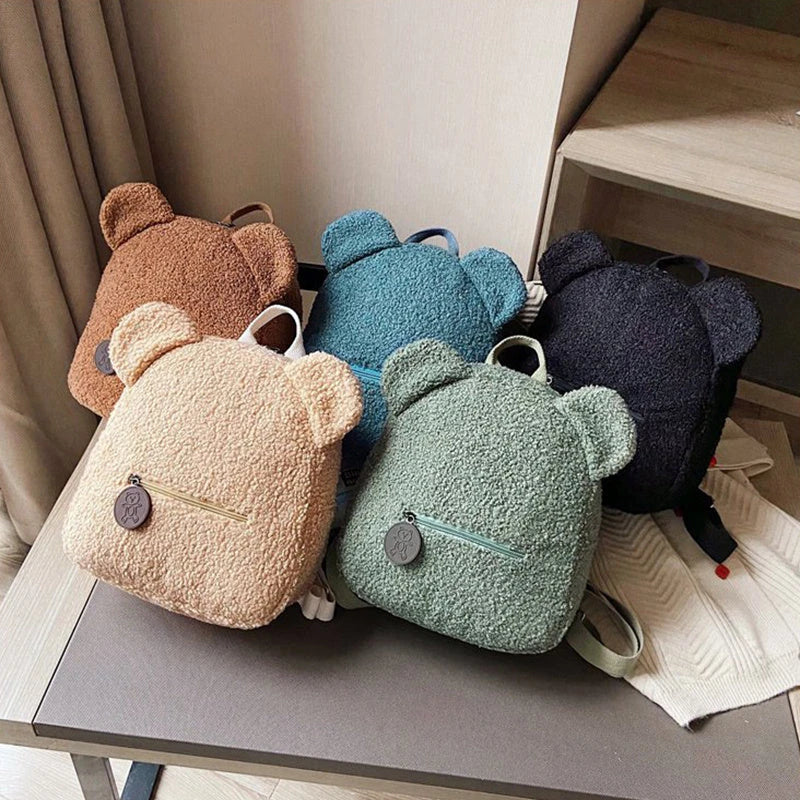 Adorable bear-shaped backpack made of soft fleece material in various colors, featuring a spacious main compartment and adjustable shoulder straps for comfortable wear.