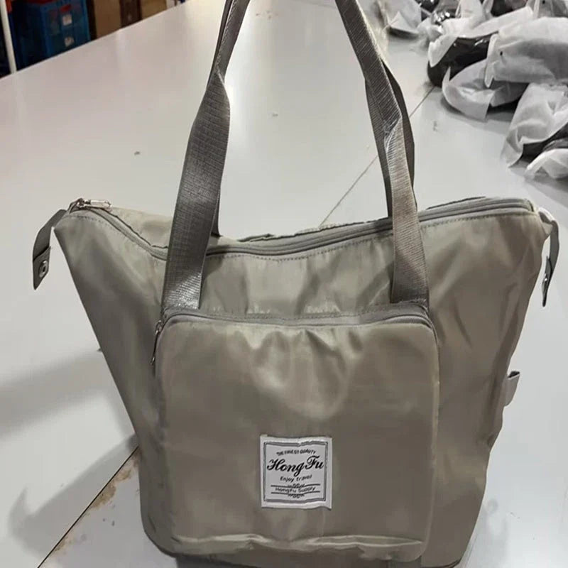 Expandable travel duffel bag with adjustable shoulder strap, multiple interior pockets, and water-resistant Oxford cloth material