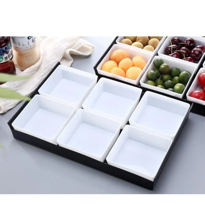 Premium British plastic snack trays in a variety of colours, including clear, white, and grey, with a black, white, or natural wood pallet for storage and display.