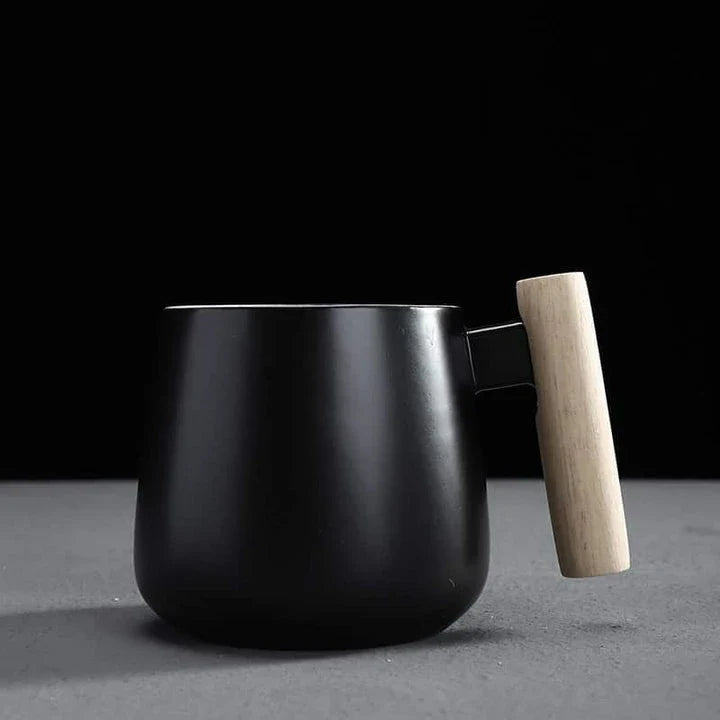 A stylish ceramic coffee mug with a colour block design and a coordinating wooden spoon