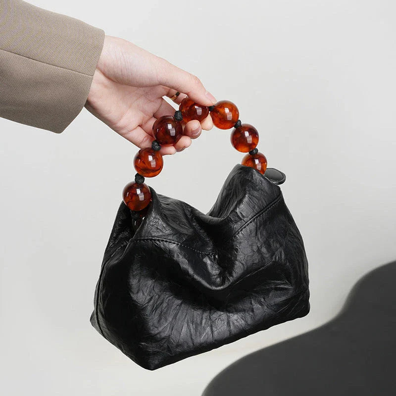 Premium leather crossbody bag with intricate beadwork, featuring a classic saddle shape and adjustable shoulder straps for versatile and secure everyday use.