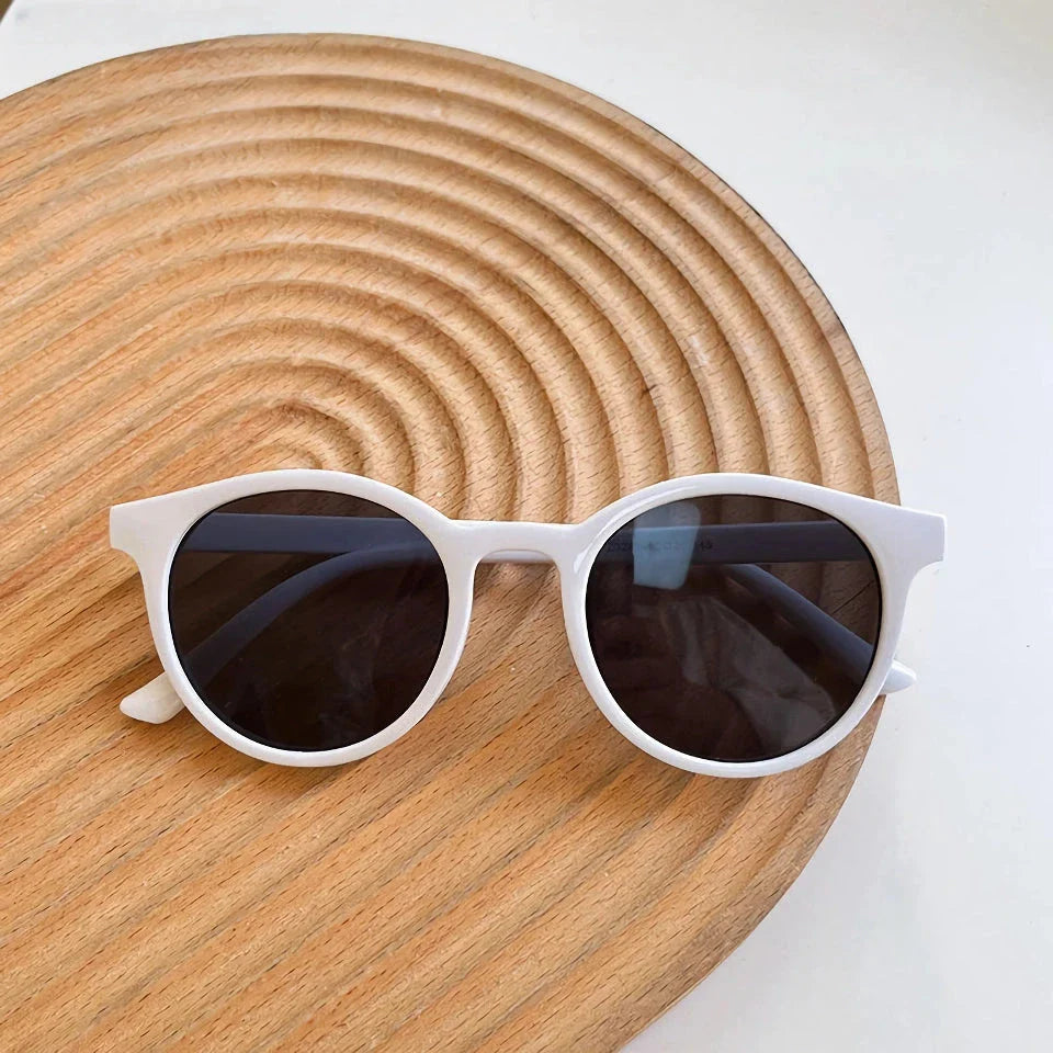 A pair of stylish, retro-inspired round sunglasses with a white frame, providing UV protection and a chic, contemporary look.