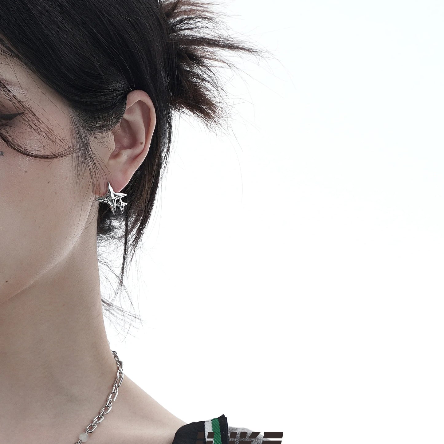 Pair of asymmetric silver stud earrings with intricate water drop and bell patterns, designed for modern British women