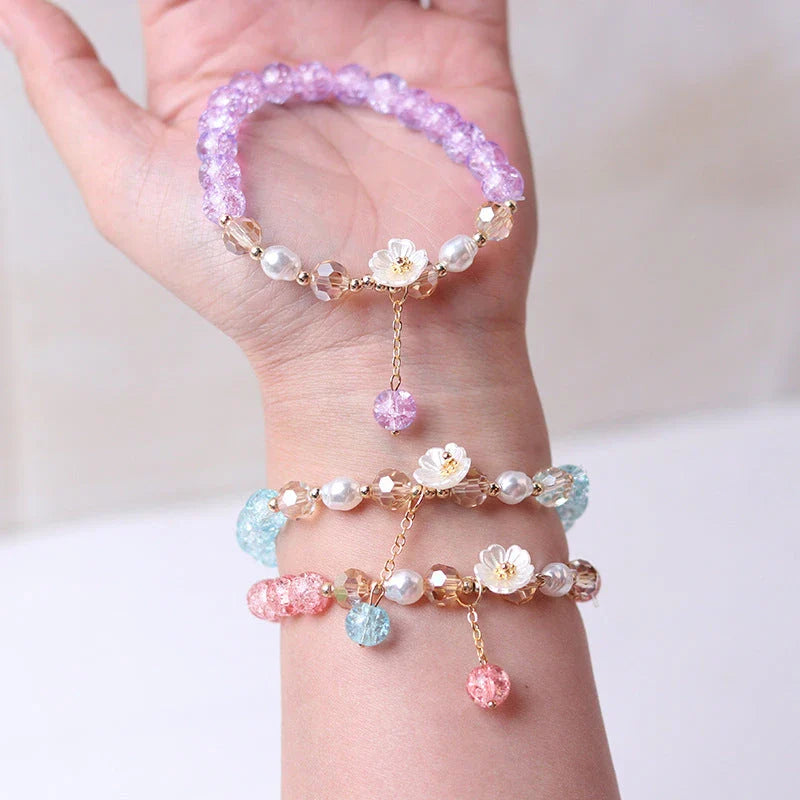 Elegant beaded bracelet with a white flower charm, vibrant purple crystal beads, and an adjustable design for a comfortable fit