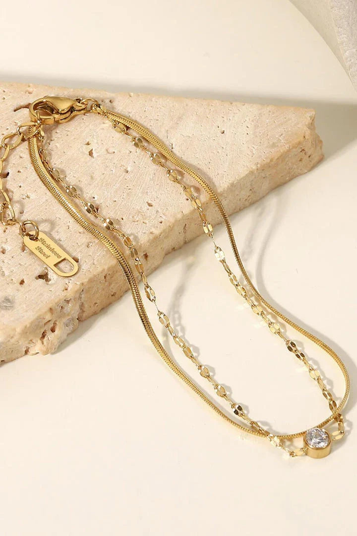 Close-up of a gold-coloured double-layered bracelet with sparkling rhinestones, on a white background.