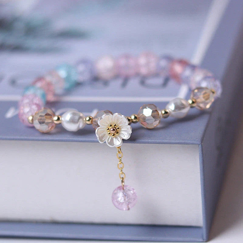 Elegant beaded bracelet with a white flower charm, vibrant purple crystal beads, and an adjustable design for a comfortable fit
