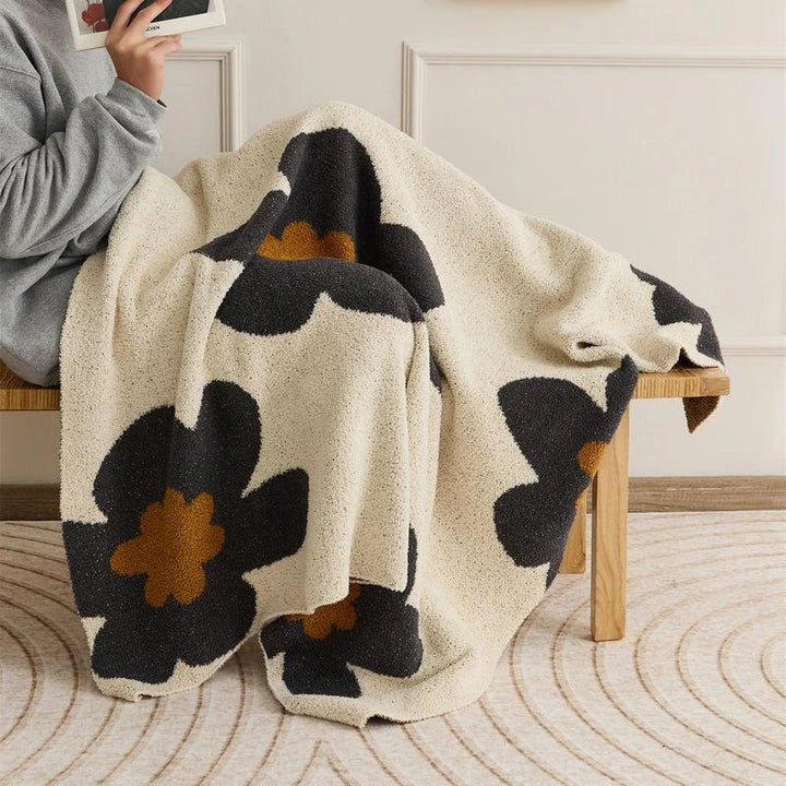 Cosy floral knitted throw blanket in red, grey, and orange colours for year-round comfort and style