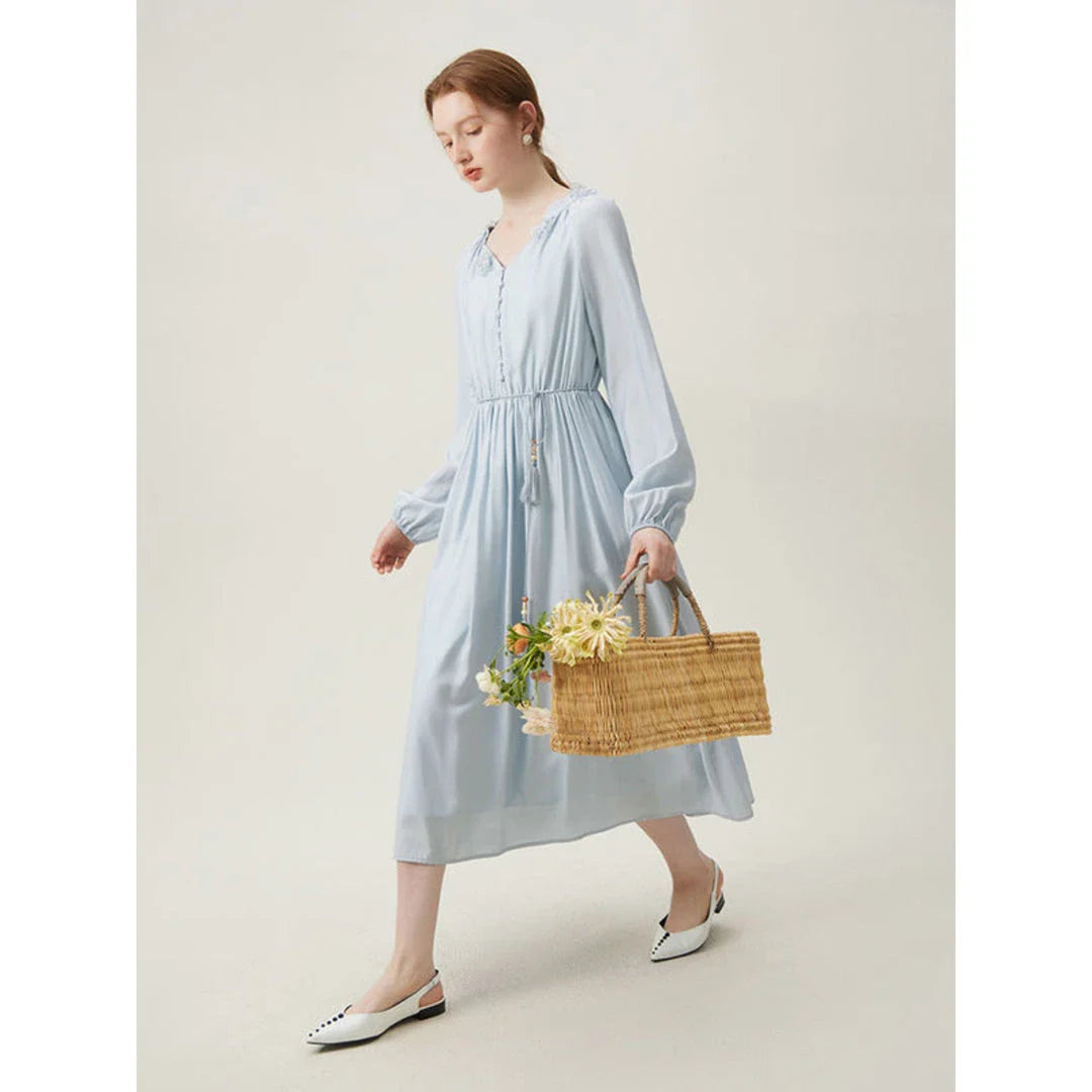 A woman wearing a long-sleeved, midi-length dress in a French pastoral style with an empire waistline and A-line silhouette.