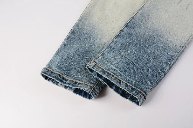 Stylish ripped denim jeans with a unique black and white patch design, perfect for British gentlemen