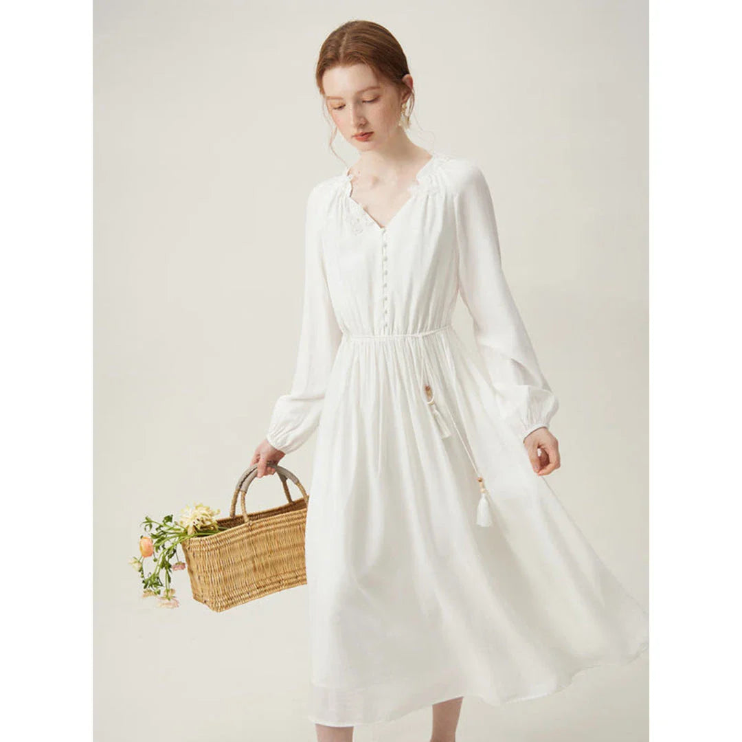 A woman wearing a long-sleeved, midi-length dress in a French pastoral style with an empire waistline and A-line silhouette.