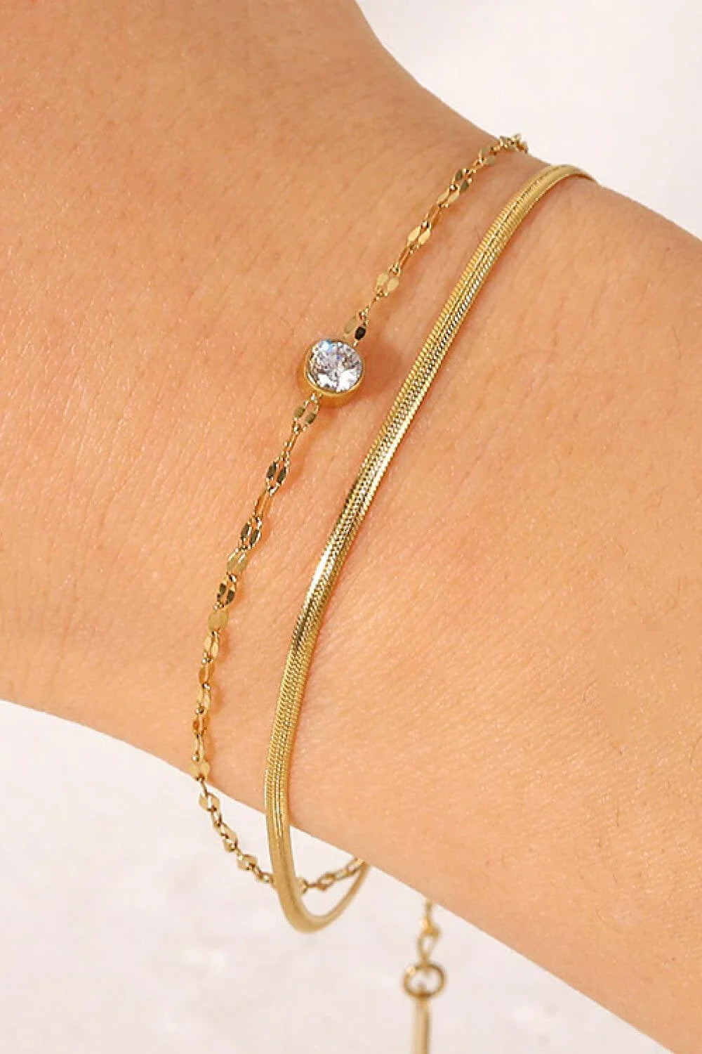 Close-up of a gold-coloured double-layered bracelet with sparkling rhinestones, on a white background.