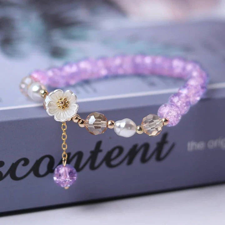 Elegant beaded bracelet with a white flower charm, vibrant purple crystal beads, and an adjustable design for a comfortable fit