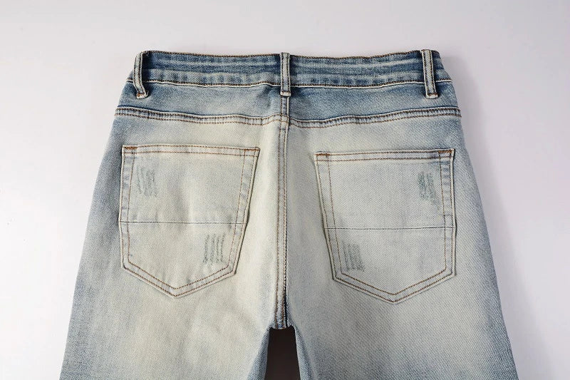 Stylish ripped denim jeans with a unique black and white patch design, perfect for British gentlemen