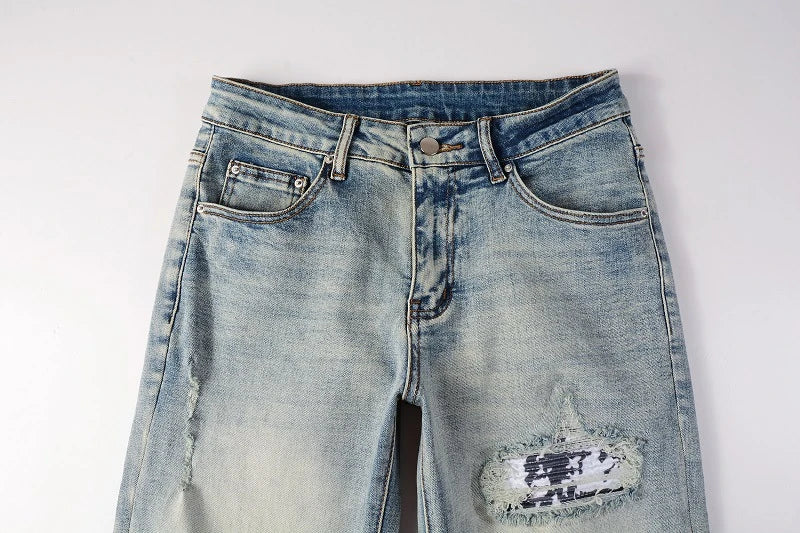 Stylish ripped denim jeans with a unique black and white patch design, perfect for British gentlemen