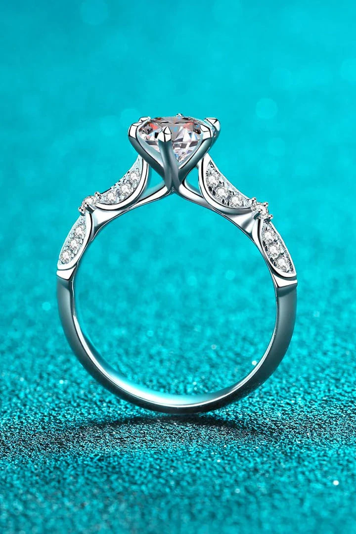 Closeup of an elegant sterling silver ring with a sparkling moissanite centre stone in a 6-prong setting
