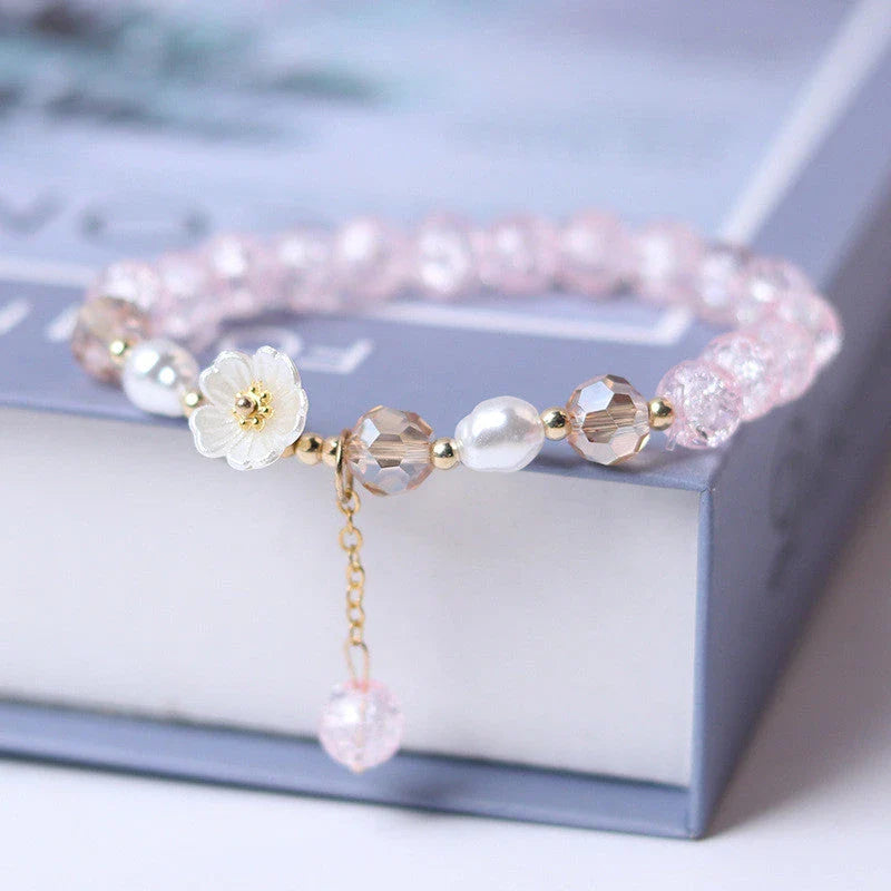 Elegant beaded bracelet with a white flower charm, vibrant purple crystal beads, and an adjustable design for a comfortable fit