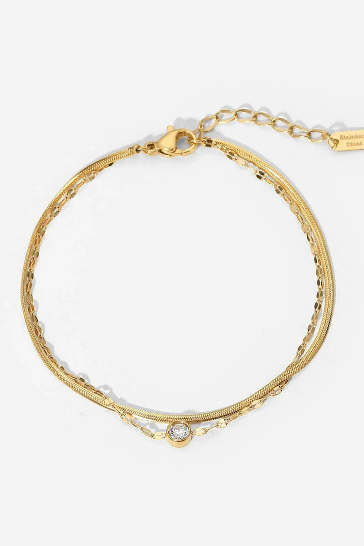 Close-up of a gold-coloured double-layered bracelet with sparkling rhinestones, on a white background.