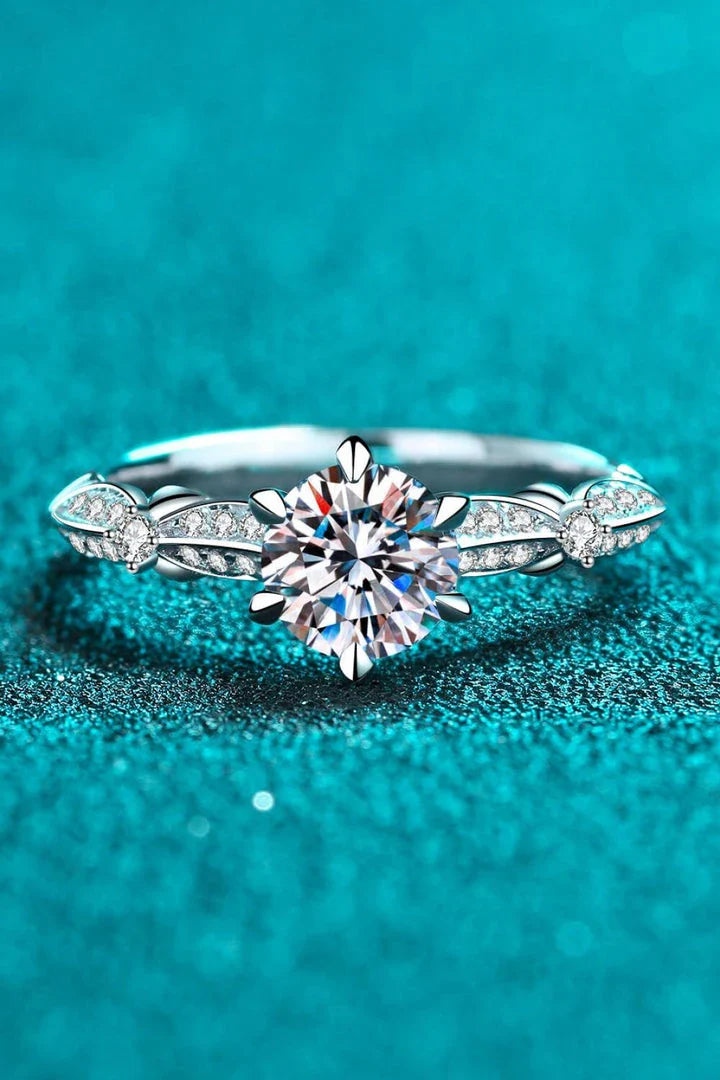Closeup of an elegant sterling silver ring with a sparkling moissanite centre stone in a 6-prong setting