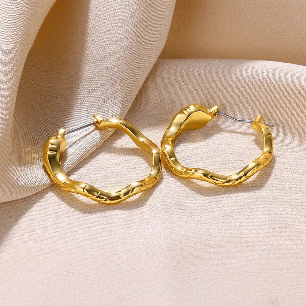 A pair of gold-toned stainless steel hoop earrings, showcasing a classic and sophisticated design
