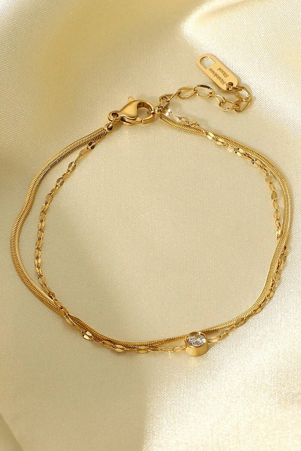 Close-up of a gold-coloured double-layered bracelet with sparkling rhinestones, on a white background.