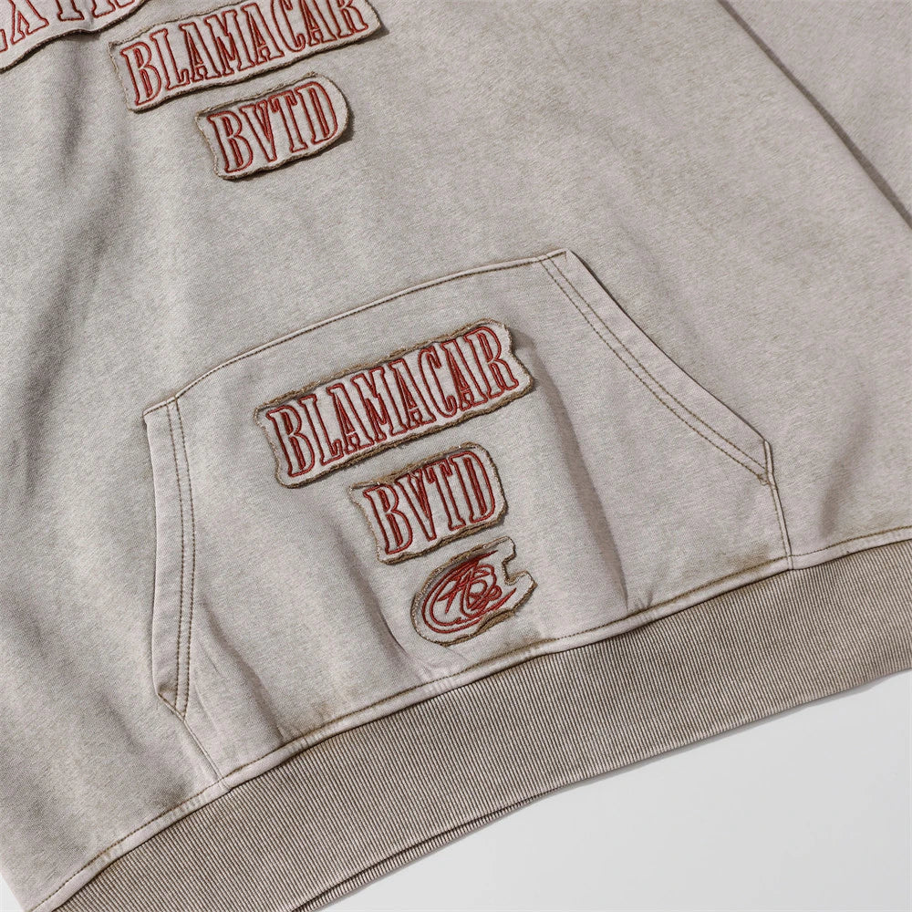 Embroidered cotton hoodie with a letter patch design, available in brown, grey, and black colours and sizes S to XL