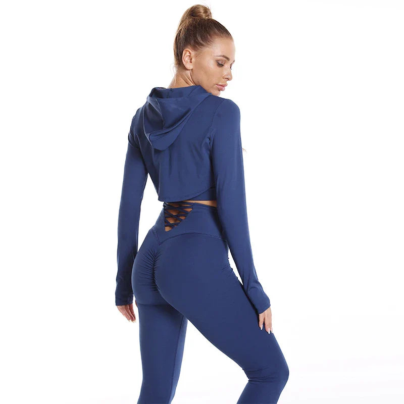 A 3-piece sports set including a hooded top, sports bra, and high-waisted leggings in a black colour scheme.