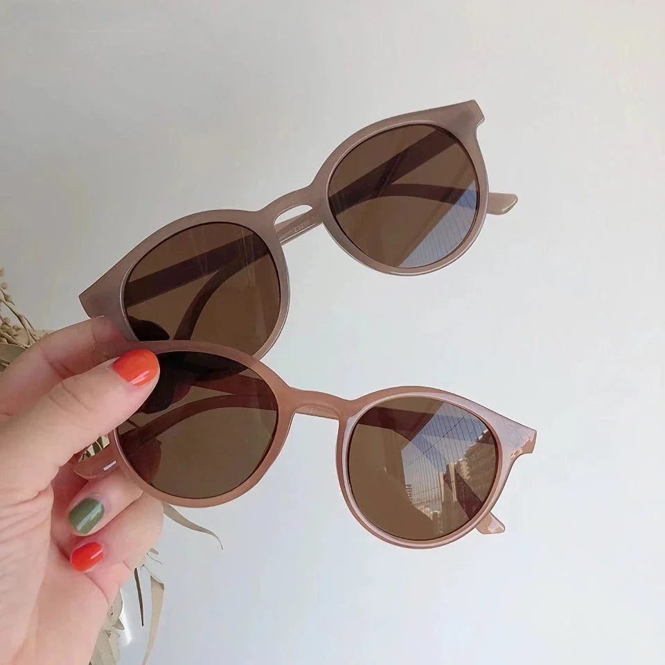 A pair of stylish, retro-inspired round sunglasses with a white frame, providing UV protection and a chic, contemporary look.