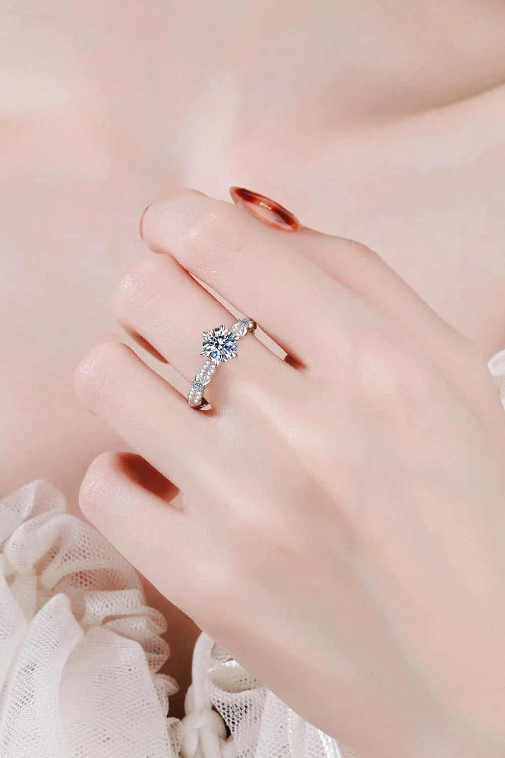 Closeup of an elegant sterling silver ring with a sparkling moissanite centre stone in a 6-prong setting